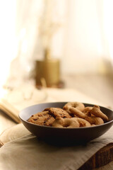 Plate of chocolate chip cookies and sugar cookies, vintage books and reading glasses, candle and flower on the table. Hygge at home. Selective focus.