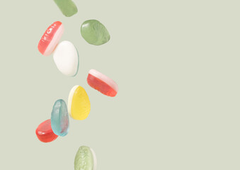 Easter eggs soft candy dropping on a pastel green background. Happy Easter minimal template.