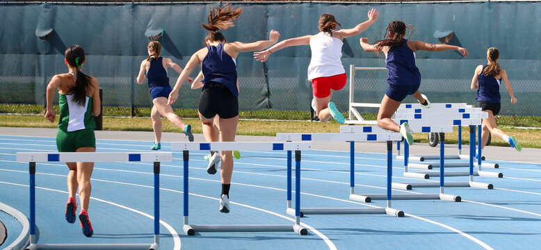 Rear view of girls running a 400 meter hurdle race