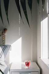 red, pink hibiscus tea on bedside table with palm tree