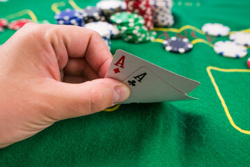 player shows two play card aces on a green table in a casino with chips.