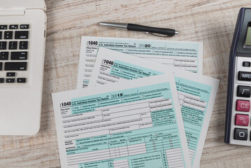 Top view tax forms 1040 with calculator, pen notebook on wooden background.