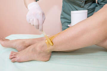 Fototapeta na wymiar The process of epilation of the legs or parts of the female body using the sugaring method.