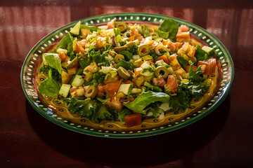 Um prato de salada sobre superfície reflexiva.