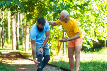 A young athlete has a leg injury while an older athlete helps him