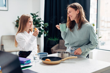Mother preparing food for her daughter before school and breakfast, too