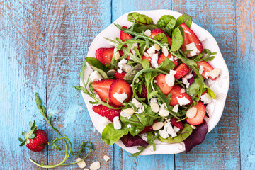 Fresh strawberry salad with spinach, arugula leaves, cheese and almond
