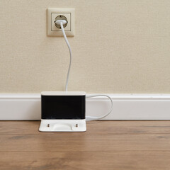 The base for charging the robot vacuum cleaner from an electrical outlet on a wooden parquet