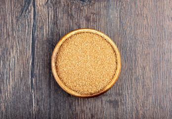 Top view of a wooden bowl with cane sugar.