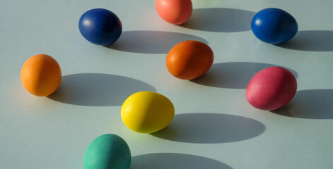 Easter eggs on blue background, with sunlight and shadows, close-up