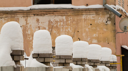 Tall beautiful columns of snow on brick pillars. An even row of small snowdrifts against the...