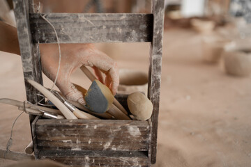 modeling tools in a wooden box. Pottery, ceramic art concept. female hand takes a paint sponge for...