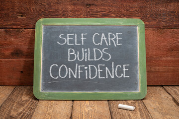 self care builds confidence, white chalk handwriting on a vintage slate blackboard against rustic...