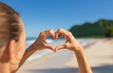 Woman making heart shape on tropical Hawaii beach.