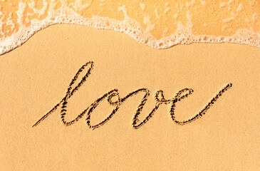 Text love written on sandy beach