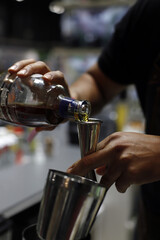 barman preparando coctel echando licor en un medidor