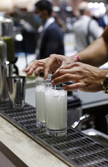 barman con sus manos da el ultimo toque a unos cocteles para servir