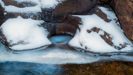 Beautiful view of a cliff near frozen water covered by snow