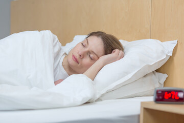 Fototapeta na wymiar Close-up photo of a woman sleeping under a blanket smiling in a dream