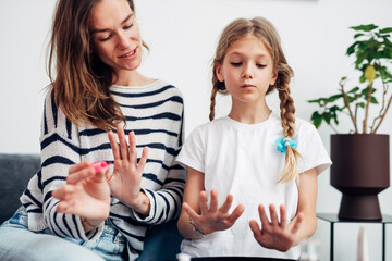 Mother and daughter doing manicure at home, painting nails with nail polish