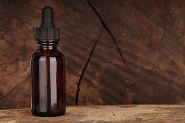 Amber glass complementing bottle on wooden background. Concept of herbal oil.