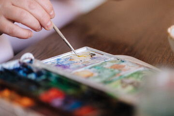 Close-up of female puts a brush into the paint