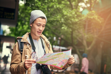 Am I heading in the right direction. Cropped shot of a young man using a map while travelling in the city.
