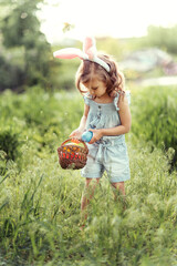 Easter egg hunt. Girl child Wearing Bunny Ears Running To Pick Up Egg In Garden. Easter tradition....