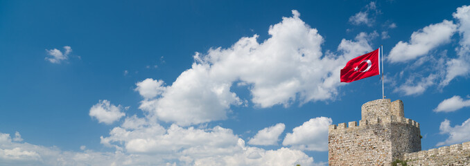 Turkish flag on historical Turkish castle. Turkish flag waving in the blue sky