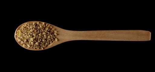 Dry bulgur pile in wooden spoon isolated on black, top view