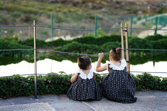 Ni&ntilde;as compartiendo hermanas amigas felices combinadas vestidas igual disfrutando platicando y viendo el lago el atardecer en el parque al aire libre