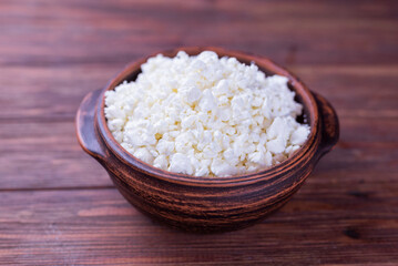 dairy product cottage cheese in a plate on a wooden background