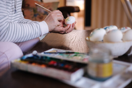 Process of woman paiting a water colors on fantasy chicken eggs. Female preparing for Easter egg festival