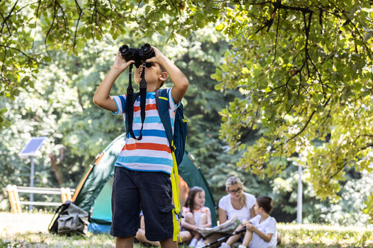 Little boy using binoculars to watch birds.He was standing in front of his friends and teacher.	
