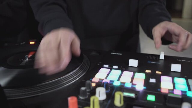 DJ spinning record at disco. Art. Close-up of DJ's hand on mixer. Glowing music panel at party. Musician's work in nightclub