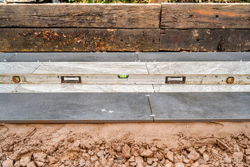Spirit level on porcelain slabs being laid to form a path in the garden of a residential property. No people.