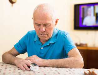 Worried elderly man measuring himself oxygen saturation at home