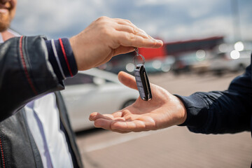Сlose up. Hand giving a car key. Concept of successful car transaction sale-purchase deal