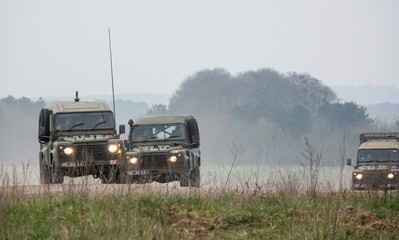 Fototapeta premium a small convoy British Army Land Rover Defender Wolf medium utility vehicles in action on a military exercise
