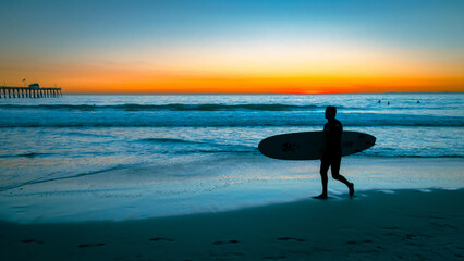 Silhouette of a guy going to surf at the San Clemente beach - obrazy, fototapety, plakaty