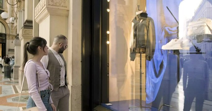 Young friends couple watch window display in Milan, Italy