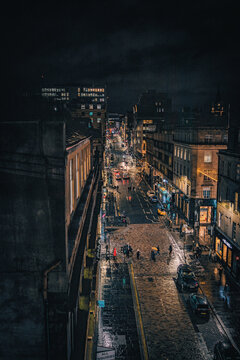 Vertical Shot Of Glasgow City Center At Night Filled With Lights And People Passing The Street