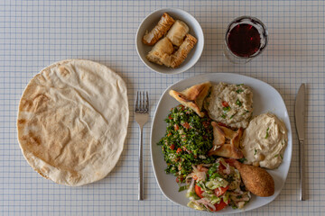 Paris, France - 03 17 2022: Top view of a plate of Lebanese specialties a pita bread and a bowl of pastries