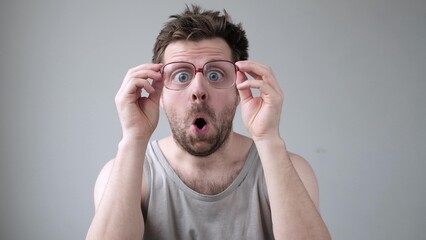 Young man looking through huge glasses in shock with surprise expression.