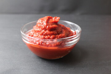 tomato sauce pasta in a glass bowl next to tomatoes on a black background with a place for text