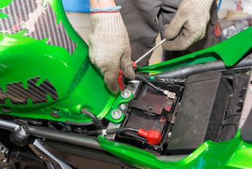 The master performs maintenance on the motorcycle. Removing the fuel tank.