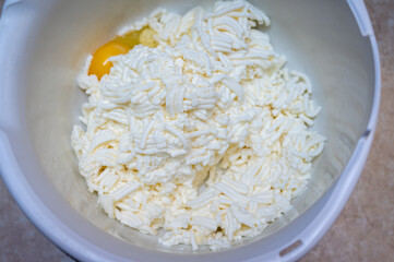 Homemade cow's cheese, ground, egg, homemade cheesecakes. Cheese in a bowl. Soft cheese in a white tall bowl. Selective focus