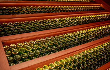 Wine cellar, storage of wine bottles. Stacks of bottles in an old dark wine cellar. Only natural light available.