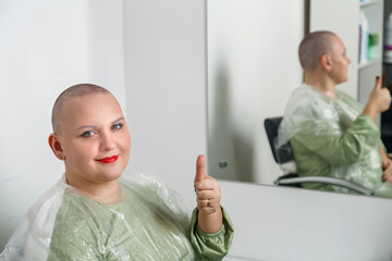 Smiling shaved bald woman with bright make-up in the hairdresser's chair shows class.