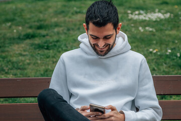 young man on bench with mobile phone